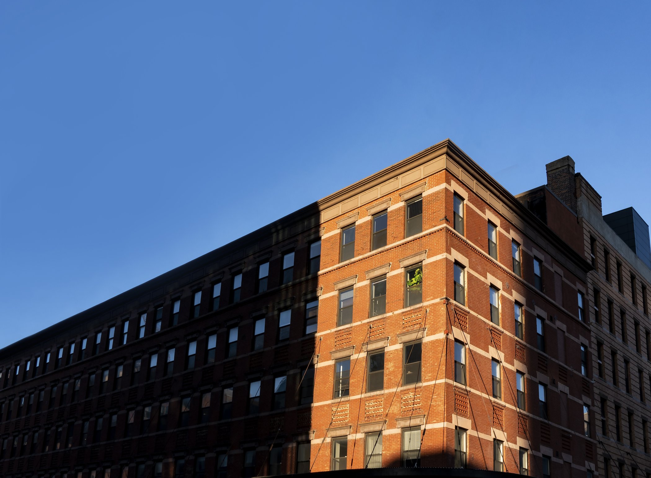 Sunlight cutting across a red brick building
