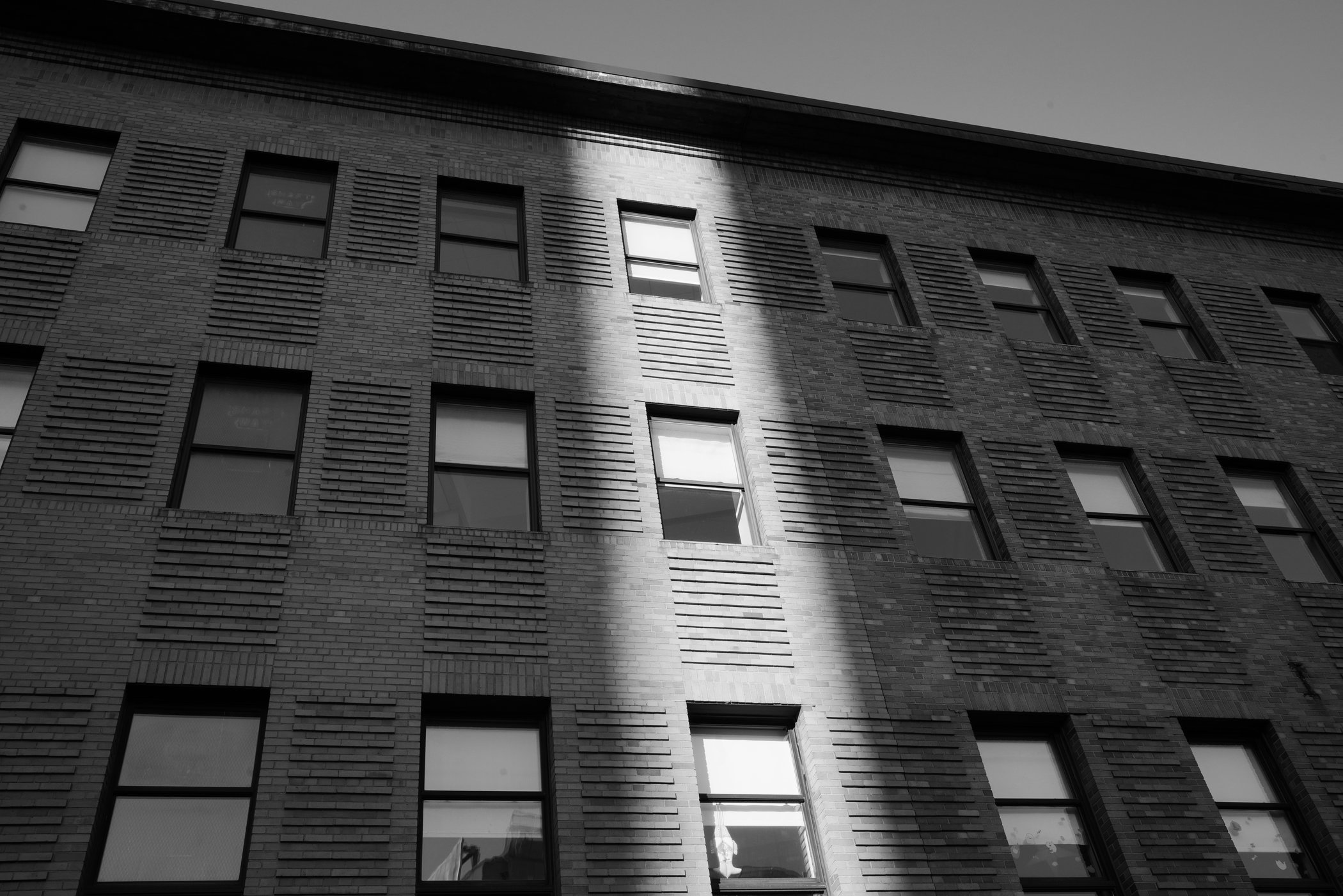 Bright vertical light crossing a brick facade and windows