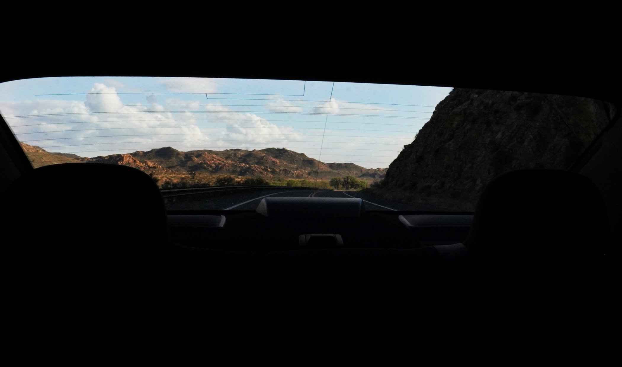 Mountain road viewed through the rear window of a car