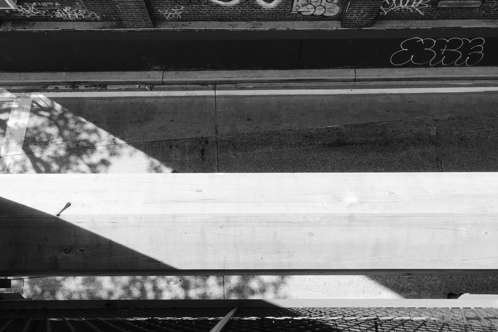 Overhead view of geometric sunlight and shadow on a sidewalk